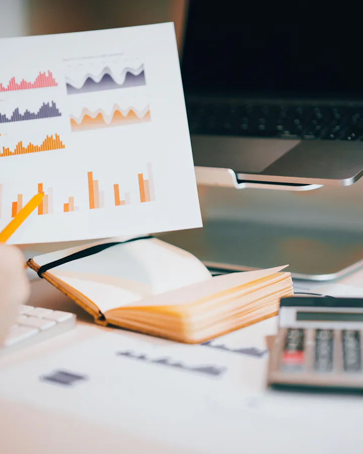 Manos revisando gráficos financieros impresos junto a una calculadora
